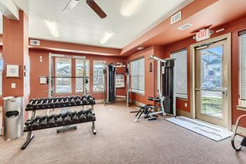 A gym with a bench, weights, and exercise equipment at Fox Run Lofts Apartments, Englewood CO.